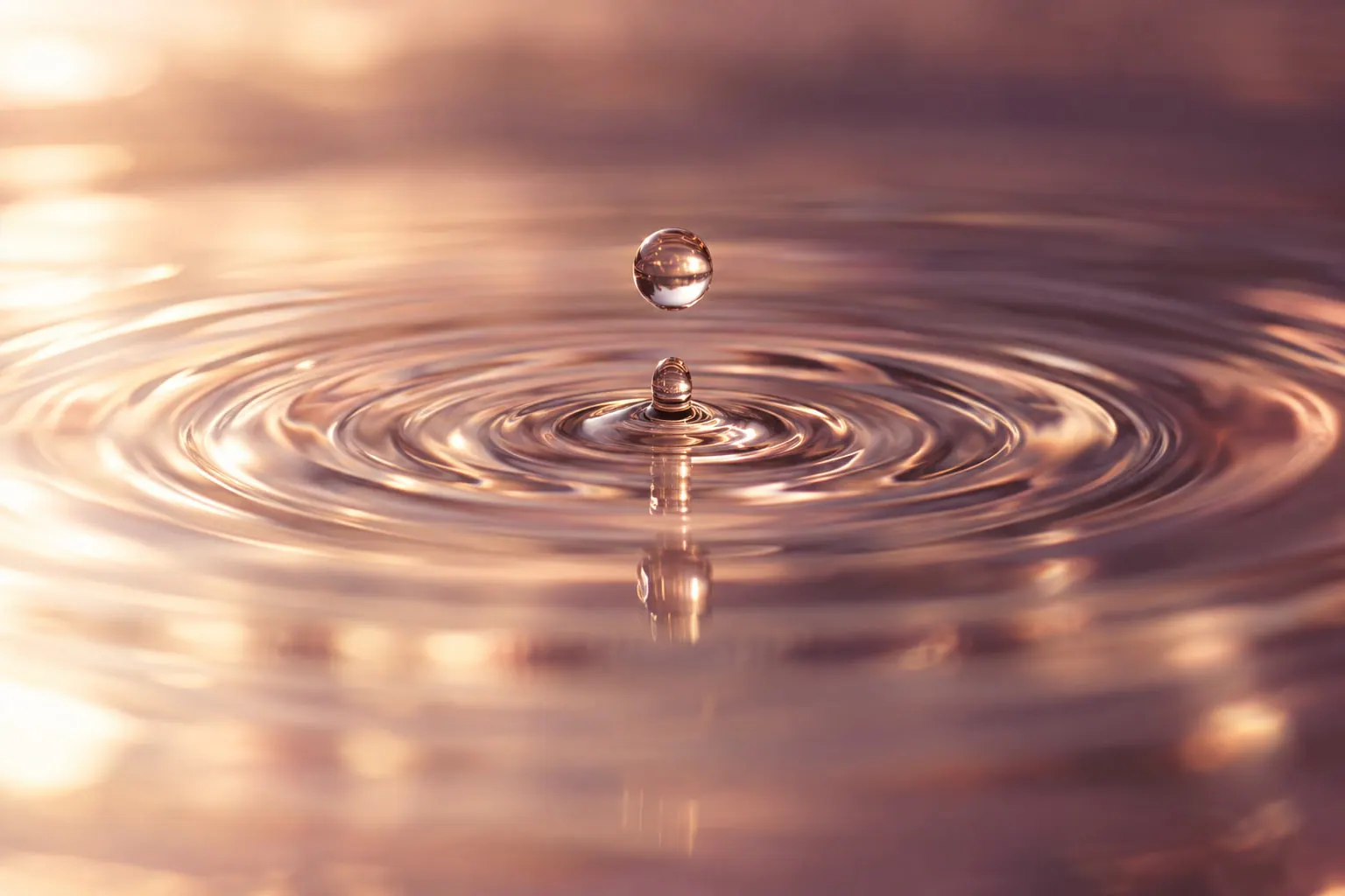 Ripples spreading across clear water over pale stone.